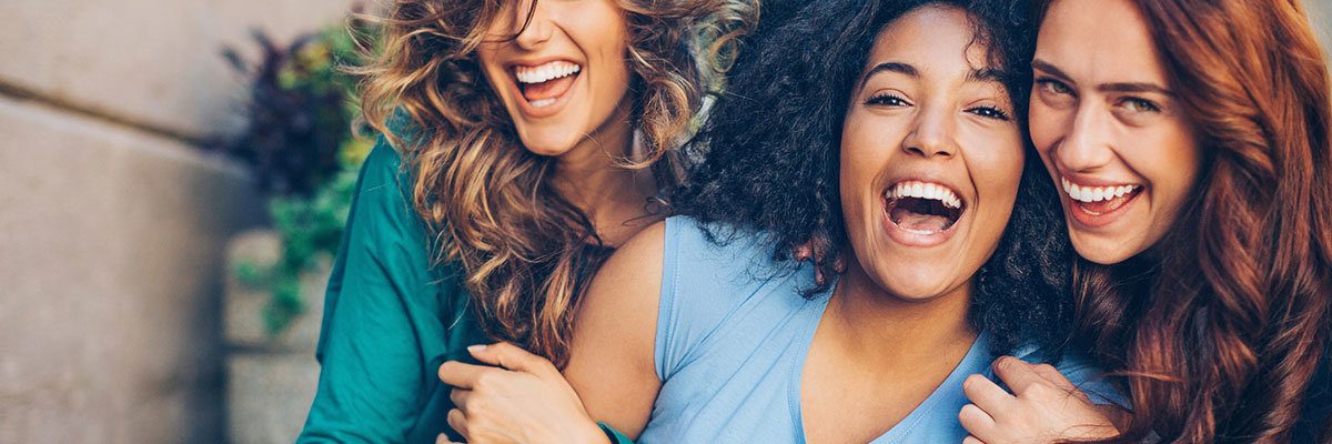 Three young women laughing outdoors